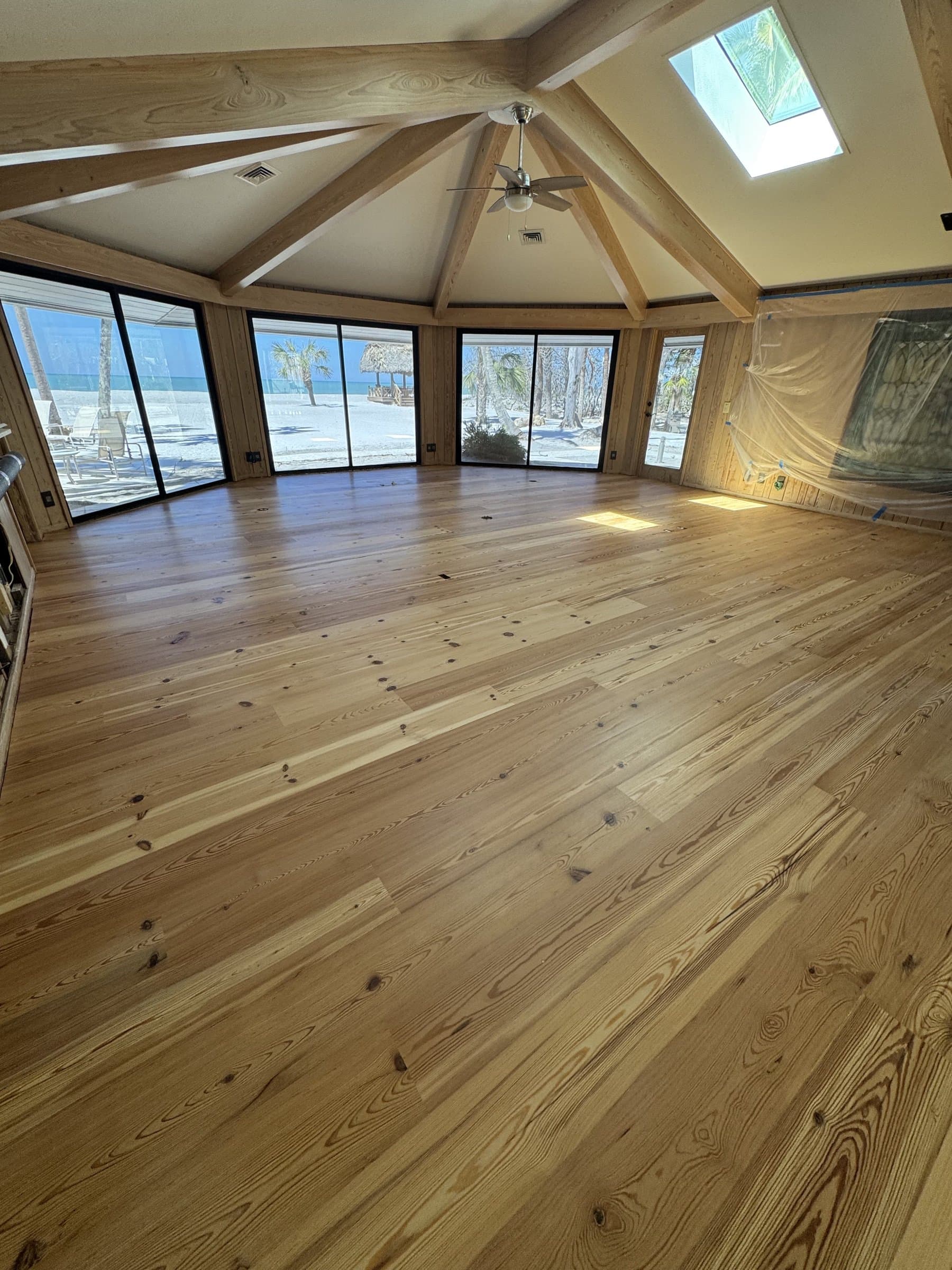 Hardwood flooring installation in a vaulted, beam-ceiling living room